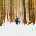Ihmisiä kävelemässä lumisessa metsässä.