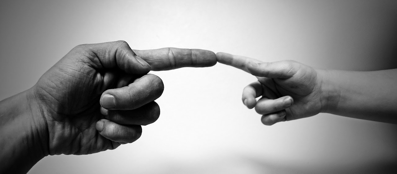 Kuva kahdesta kädestä, joiden etusormet osuvat toisiinsa.