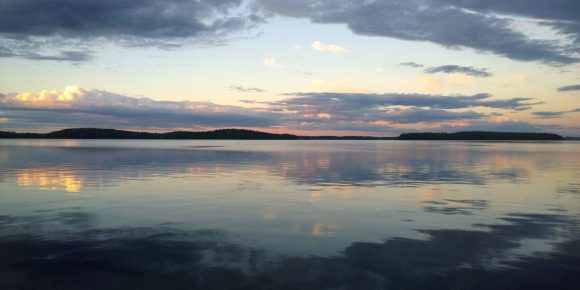 Näkymä Kyrösjärvelle, järven pinta on tyyni ja siitä heijastuu punertava taivas pilvineen.